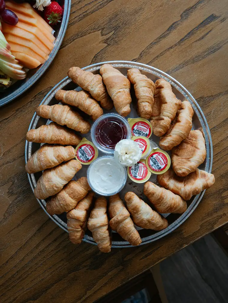 Breakfast catering platter of butter croissants with jam and butter in the centre