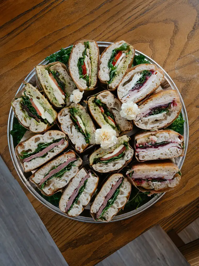 Catering tray of assorted sandwich halves including pesto chicken, turkey cranberry and roast beef